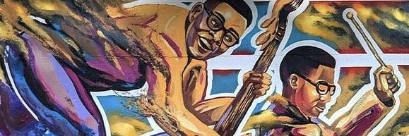 A colorful mural depicts two Black musicians wearing glasses, one playing a guitar and the other playing drums, against a vibrant background with dynamic brushstrokes and abstract shapes.
